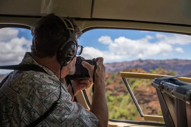 Un pasajero con auriculares fotografiando el cañón de Waimea desde un helicóptero