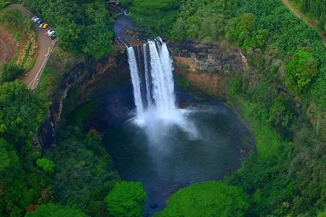 Ein Wasserfall stürzt in ein rundes, von Wald umgebenes Becken